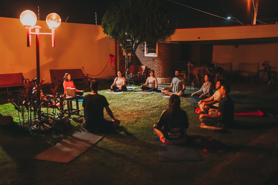Group of people meditating in a circle outdoors at night