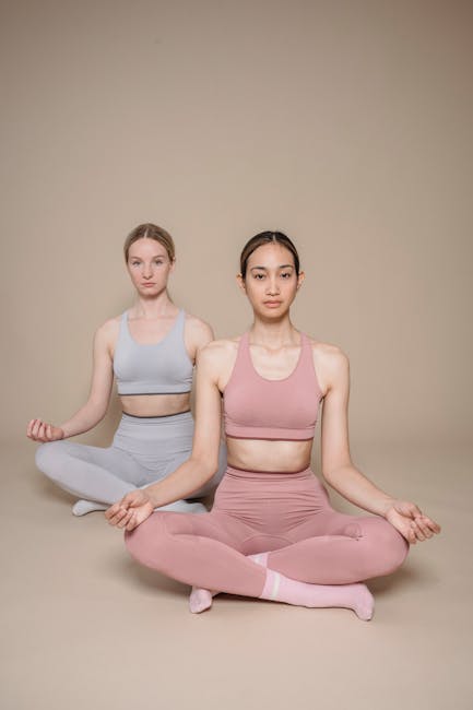 Two women in fitness attire practicing meditation